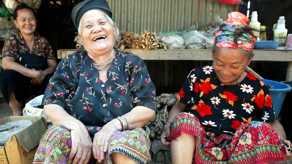 Two Thai women smiling and being welcoming.