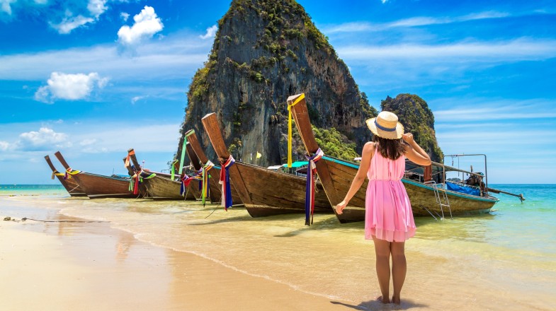 A woman on the beach or island in Thailand with a mountain.