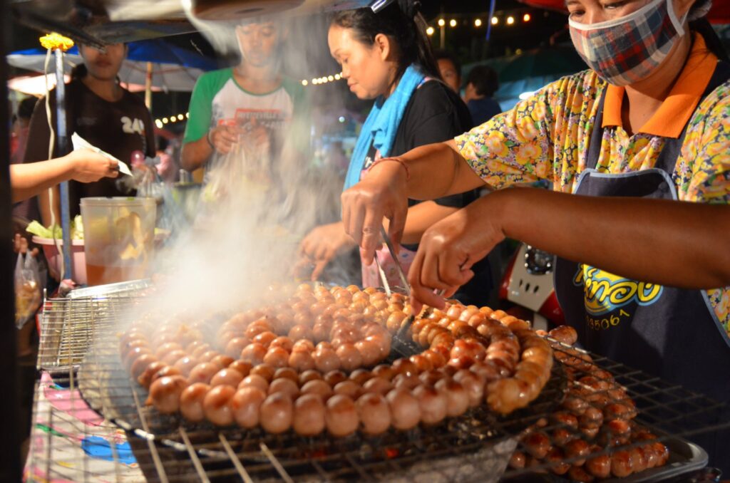 A woman cooking sai krok isaan.