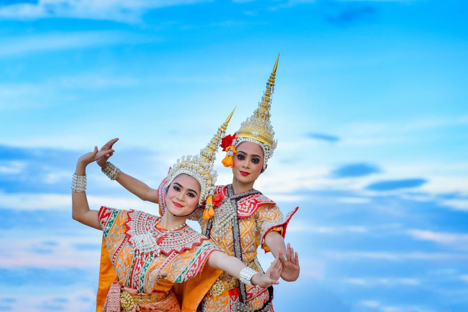 Two Thai dancers wearing traditional Thai dress doing a Thai dance.